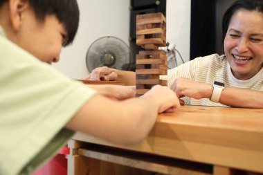 Güneydoğu Asyalı çocuk annesiyle tahta kule oyunu oynuyor..