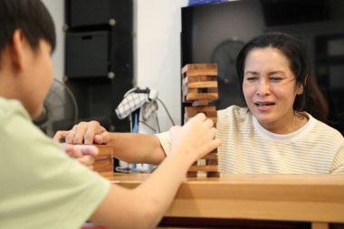 Güneydoğu Asyalı çocuk annesiyle tahta kule oyunu oynuyor..