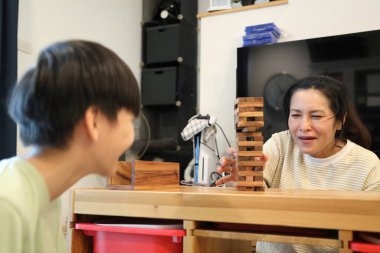 Güneydoğu Asyalı çocuk annesiyle tahta kule oyunu oynuyor..