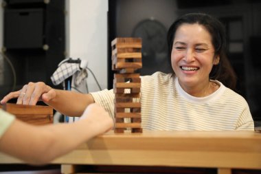 Güneydoğu Asyalı çocuk annesiyle tahta kule oyunu oynuyor..