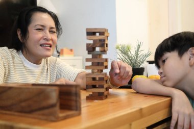 Güneydoğu Asyalı çocuk annesiyle tahta kule oyunu oynuyor..