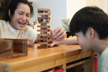 Güneydoğu Asyalı çocuk annesiyle tahta kule oyunu oynuyor..
