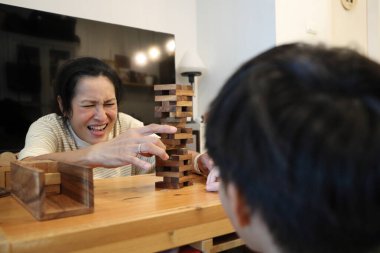 Güneydoğu Asyalı çocuk annesiyle tahta kule oyunu oynuyor..