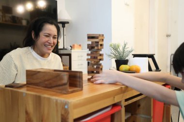 Güneydoğu Asyalı çocuk annesiyle tahta kule oyunu oynuyor..