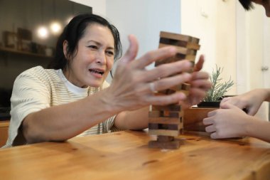 Güneydoğu Asyalı çocuk annesiyle tahta kule oyunu oynuyor..