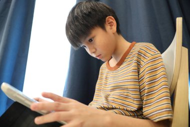 Güneydoğu Asyalı çocuk oturma odasında dijital tablet kullanıyor..