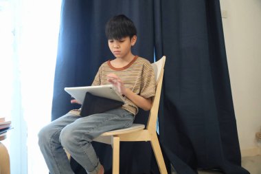 Güneydoğu Asyalı çocuk oturma odasında dijital tablet kullanıyor..