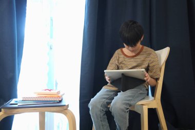 Güneydoğu Asyalı çocuk oturma odasında dijital tablet kullanıyor..