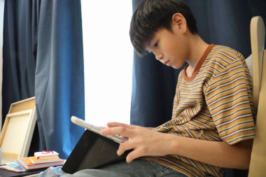 Güneydoğu Asyalı çocuk oturma odasında dijital tablet kullanıyor..