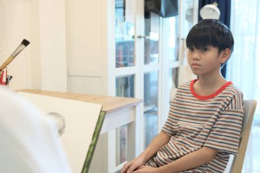 Güneydoğu Asya 'lı bekar anne oğlunun hareketsiz otururken resmini çiziyor..