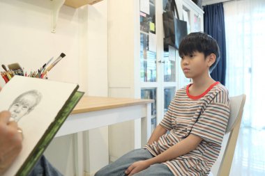 Güneydoğu Asya 'lı bekar anne oğlunun hareketsiz otururken resmini çiziyor..