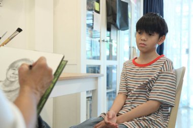 Güneydoğu Asya 'lı bekar anne oğlunun hareketsiz otururken resmini çiziyor..