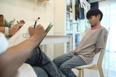 Güneydoğu Asya 'lı bekar anne oğlunun hareketsiz otururken resmini çiziyor..