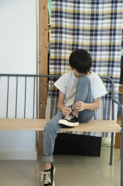 Güneydoğu Asyalı çocuk evden çıkmadan önce ayakkabılarını giyiyor..