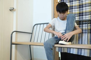 Güneydoğu Asyalı çocuk evden çıkmadan önce ayakkabılarını giyiyor..