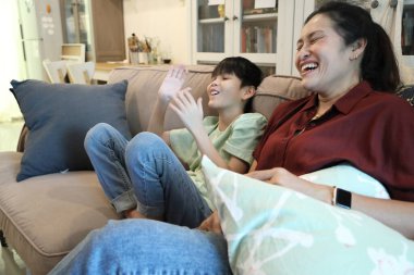 Güneydoğu Asya 'lı bekar anne, genç oğlunun televizyonda oyun oynamasını izliyor..