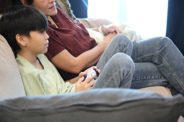 Güneydoğu Asya 'lı bekar anne, genç oğlunun televizyonda oyun oynamasını izliyor..