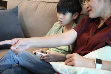 Güneydoğu Asya 'lı bekar anne, genç oğlunun televizyonda oyun oynamasını izliyor..