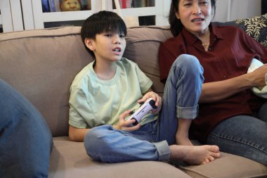 Güneydoğu Asya 'lı bekar anne, genç oğlunun televizyonda oyun oynamasını izliyor..