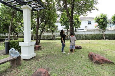 Güneydoğu Asya 'lı bekar bir anne çocuğuyla parkta vakit geçirir ve bitki, böcek ve doğal çevre gibi doğa temelli öğrenme faaliyetleriyle ilgilenir..