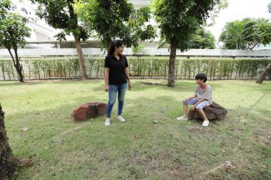 Güneydoğu Asya 'lı bekar bir anne çocuğuyla parkta vakit geçirir ve bitki, böcek ve doğal çevre gibi doğa temelli öğrenme faaliyetleriyle ilgilenir..