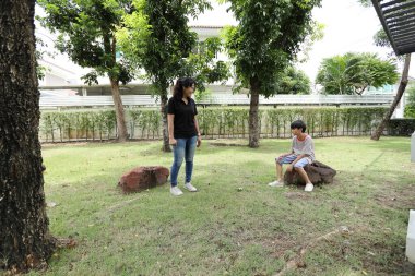Güneydoğu Asya 'lı bekar bir anne çocuğuyla parkta vakit geçirir ve bitki, böcek ve doğal çevre gibi doğa temelli öğrenme faaliyetleriyle ilgilenir..