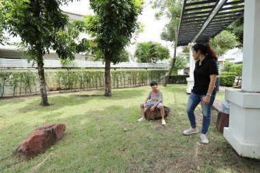 Güneydoğu Asya 'lı bekar bir anne çocuğuyla parkta vakit geçirir ve bitki, böcek ve doğal çevre gibi doğa temelli öğrenme faaliyetleriyle ilgilenir..
