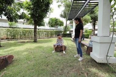 Güneydoğu Asya 'lı bekar bir anne çocuğuyla parkta vakit geçirir ve bitki, böcek ve doğal çevre gibi doğa temelli öğrenme faaliyetleriyle ilgilenir..