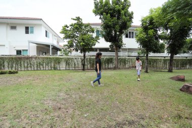 Güneydoğu Asya 'lı bekar bir anne çocuğuyla parkta vakit geçirir ve bitki, böcek ve doğal çevre gibi doğa temelli öğrenme faaliyetleriyle ilgilenir..