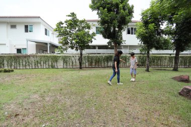 Güneydoğu Asya 'lı bekar bir anne çocuğuyla parkta vakit geçirir ve bitki, böcek ve doğal çevre gibi doğa temelli öğrenme faaliyetleriyle ilgilenir..