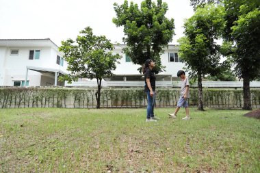 Güneydoğu Asya 'lı bekar bir anne çocuğuyla parkta vakit geçirir ve bitki, böcek ve doğal çevre gibi doğa temelli öğrenme faaliyetleriyle ilgilenir..