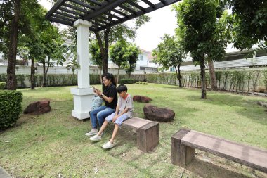 Güneydoğu Asya 'lı bekar bir anne çocuğuyla parkta vakit geçirir ve bitki, böcek ve doğal çevre gibi doğa temelli öğrenme faaliyetleriyle ilgilenir..