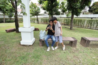 Güneydoğu Asya 'lı bekar bir anne çocuğuyla parkta vakit geçirir ve bitki, böcek ve doğal çevre gibi doğa temelli öğrenme faaliyetleriyle ilgilenir..