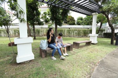 Güneydoğu Asya 'lı bekar bir anne çocuğuyla parkta vakit geçirir ve bitki, böcek ve doğal çevre gibi doğa temelli öğrenme faaliyetleriyle ilgilenir..