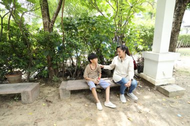 Güneydoğu Asya 'lı bekar bir anne çocuğuyla parkta vakit geçirir ve bitki, böcek ve doğal çevre gibi doğa temelli öğrenme faaliyetleriyle ilgilenir..