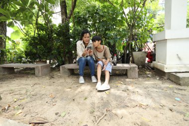 Güneydoğu Asya 'lı bekar bir anne çocuğuyla parkta vakit geçirir ve bitki, böcek ve doğal çevre gibi doğa temelli öğrenme faaliyetleriyle ilgilenir..