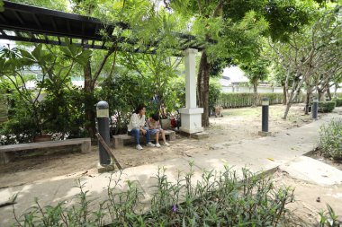 Güneydoğu Asya 'lı bekar bir anne çocuğuyla parkta vakit geçirir ve bitki, böcek ve doğal çevre gibi doğa temelli öğrenme faaliyetleriyle ilgilenir..