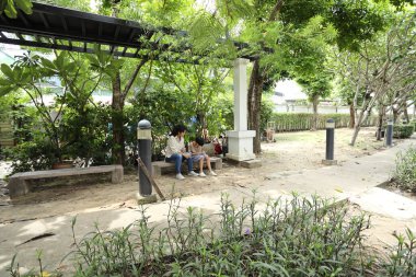 Güneydoğu Asya 'lı bekar bir anne çocuğuyla parkta vakit geçirir ve bitki, böcek ve doğal çevre gibi doğa temelli öğrenme faaliyetleriyle ilgilenir..