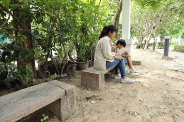 Güneydoğu Asya 'lı bekar bir anne çocuğuyla parkta vakit geçirir ve bitki, böcek ve doğal çevre gibi doğa temelli öğrenme faaliyetleriyle ilgilenir..