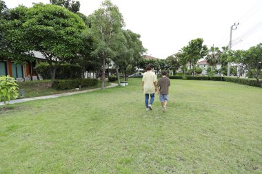 Güneydoğu Asya 'lı bekar bir anne çocuğuyla parkta vakit geçirir ve bitki, böcek ve doğal çevre gibi doğa temelli öğrenme faaliyetleriyle ilgilenir..