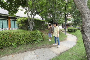 Güneydoğu Asya 'lı bekar bir anne çocuğuyla parkta vakit geçirir ve bitki, böcek ve doğal çevre gibi doğa temelli öğrenme faaliyetleriyle ilgilenir..