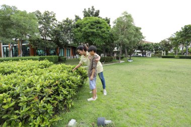 Güneydoğu Asya 'lı bekar bir anne çocuğuyla parkta vakit geçirir ve bitki, böcek ve doğal çevre gibi doğa temelli öğrenme faaliyetleriyle ilgilenir..