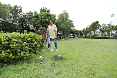 Güneydoğu Asya 'lı bekar bir anne çocuğuyla parkta vakit geçirir ve bitki, böcek ve doğal çevre gibi doğa temelli öğrenme faaliyetleriyle ilgilenir..