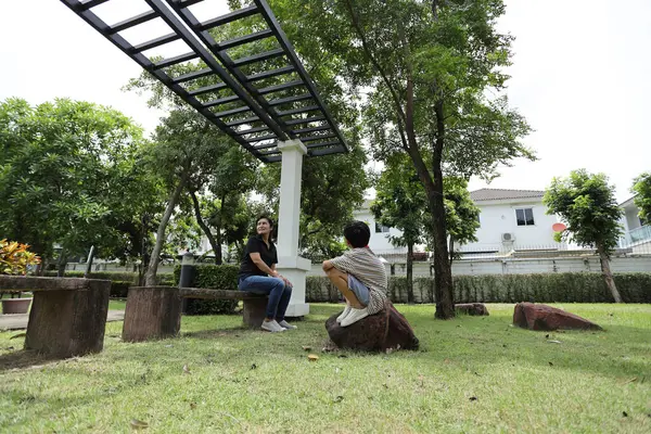 Güneydoğu Asya 'lı bekar bir anne çocuğuyla parkta vakit geçirir ve bitki, böcek ve doğal çevre gibi doğa temelli öğrenme faaliyetleriyle ilgilenir..