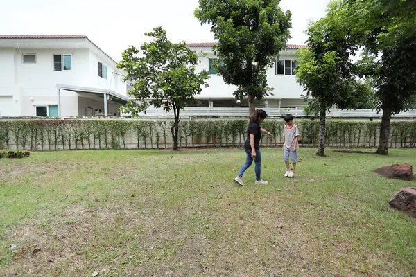 Güneydoğu Asya 'lı bekar bir anne çocuğuyla parkta vakit geçirir ve bitki, böcek ve doğal çevre gibi doğa temelli öğrenme faaliyetleriyle ilgilenir..