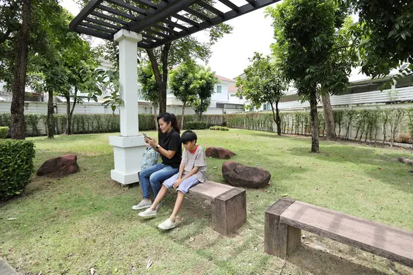 Güneydoğu Asya 'lı bekar bir anne çocuğuyla parkta vakit geçirir ve bitki, böcek ve doğal çevre gibi doğa temelli öğrenme faaliyetleriyle ilgilenir..