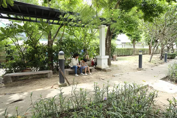 Güneydoğu Asya 'lı bekar bir anne çocuğuyla parkta vakit geçirir ve bitki, böcek ve doğal çevre gibi doğa temelli öğrenme faaliyetleriyle ilgilenir..