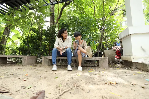 Güneydoğu Asya 'lı bekar bir anne çocuğuyla parkta vakit geçirir ve bitki, böcek ve doğal çevre gibi doğa temelli öğrenme faaliyetleriyle ilgilenir..