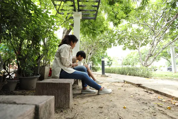 Güneydoğu Asya 'lı bekar bir anne çocuğuyla parkta vakit geçirir ve bitki, böcek ve doğal çevre gibi doğa temelli öğrenme faaliyetleriyle ilgilenir..
