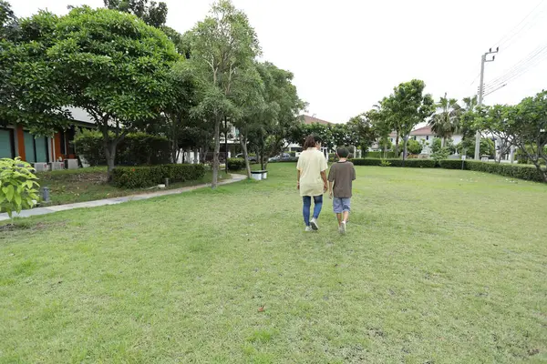 Güneydoğu Asya 'lı bekar bir anne çocuğuyla parkta vakit geçirir ve bitki, böcek ve doğal çevre gibi doğa temelli öğrenme faaliyetleriyle ilgilenir..